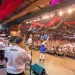Foto na Oktoberfest Blumenau, um palco onde há pessoas festejando. Na frente aparece o público, uma multidão